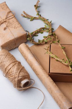 El yapımı Noel hediyeleri paketleme işlemi. Kağıt, kutu ve jüt halat makarası beyaz masada. Kış tatili çevre dostu çalışma.