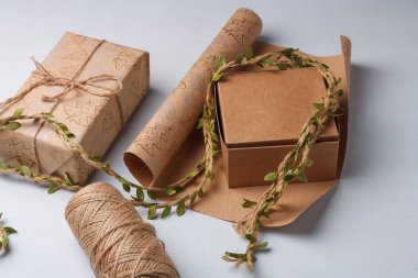Çevre dostu Noel hediyeleri paketleniyor. Doğal Yeni Yıl dekorasyonları hakkında farkındalık. Kağıt rulo, ip makarası beyaz masada.