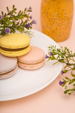 Pembe arka planda çiçekli bir tabak kurabiye. Şişede iç. Tatlı pasta, fırın ürünleri, tatlılar, tatlı..