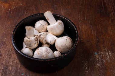 Mutfak masasında taze çiğ şampiyon mantarı kasesi. Sonbahar hasadı, mevsimlik jrganik vegan yemekleri, sağlıklı yeme alışkanlıkları..