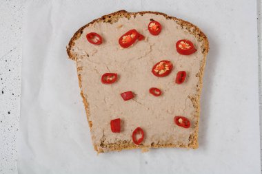 Tavuk etli sandviç ya da salça, beyaz kağıtta kırmızı biber dilimleri, yakın çekim, üst manzara. Lezzetli çerez, lezzetli aperatif, hızlı öğle yemeği.