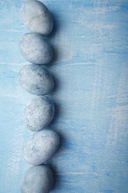 Mavi arka planda boyalı Paskalya yumurtaları. Bahar tatili, sembolik yemekler. Üst görünüm, boşluğu kopyala. Dikey çekim