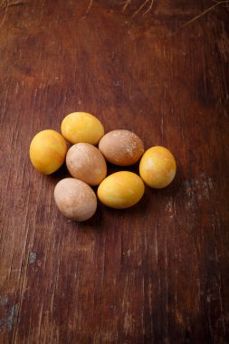 Kahverengi ahşap masada renkli paskalya yumurtaları. Üst görüntü, dikey çekim, kopyalama alanı. Paskalya arkaplanı