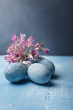 Mavi arka planda mor çiçeklerle boyanmış Paskalya yumurtaları. Bahar bayramı sembolü. Uzayı kopyala Dikey çekim