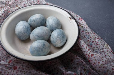 Paskalya yumurtaları gri ahşap arka planda mutfak havlusuyla maviye boyandı. Boşluğu kopyala