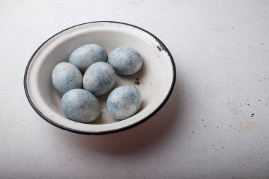 Paskalya yumurtaları ahşap arka planda beyaz kâseye maviye boyanmış. Boşluğu kopyala