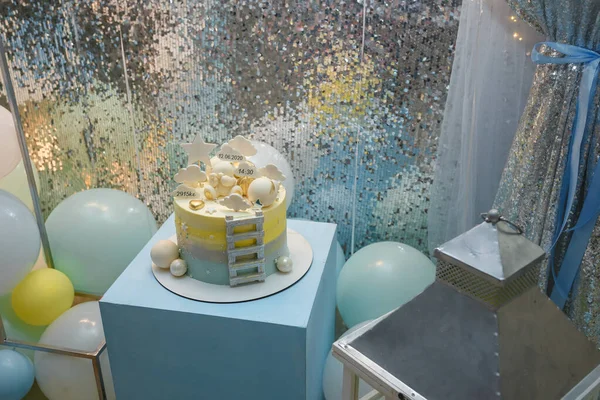Mavi küpün üzerinde duran 1 yaşındaki çocuk doğum günü pastası. Bulutlar, yıldızlı tepecikler, bebek ağırlığında, pastanın üstünde oyuncak ayı.