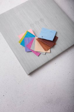 Photo album, photo book with grey leather cover and some multicolored samples on white background. Vertical shot, copy space