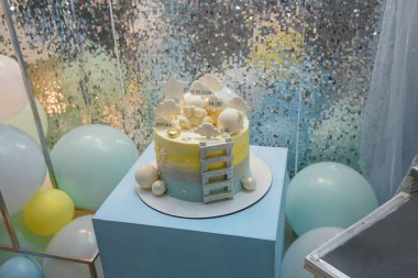 Mavi küpün üzerinde duran 1 yaşındaki çocuk doğum günü pastası. Bulutlar, yıldızlı tepecikler, bebek ağırlığında, pastanın üstünde oyuncak ayı.