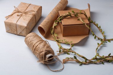Çevre dostu Noel hediyeleri paketleniyor. Doğal Yeni Yıl dekorasyonları hakkında farkındalık. Kağıt rulo, ip makarası beyaz masada.