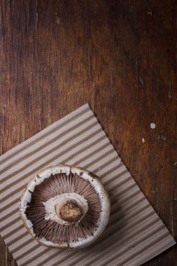 Kağıt üzerinde taze bir şampiyon mantarı ve ahşap arka plan. Mevsimlik ogranik ürün, sağlıklı protein gıdası. Dikey çekim, boşluğu kopyala