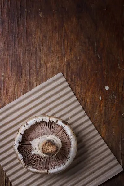 Kağıt üzerinde taze bir şampiyon mantarı ve ahşap arka plan. Mevsimlik ogranik ürün, sağlıklı protein gıdası. Dikey çekim, boşluğu kopyala