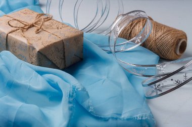 Mutlu Noeller hediye kutusunun paketlenmesi devam ediyor. El işi kağıdı, gümüş kurdele bandı, arka planda ip makarası. DIY Paketleme