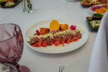 Aperatifli şölen masası. Yenilebilir yonca ya da karanfil çiçekleriyle süslenmiş ekmek, et, domates ve peynirli tabak, yakın çekim.