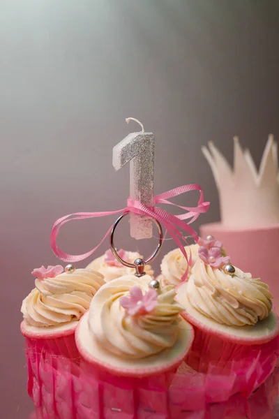 女婴一岁生日糖果棒 有奶油和粉红色花朵的白色纸杯蛋糕 银光1号形状的蜡烛 招待客人 — 图库照片