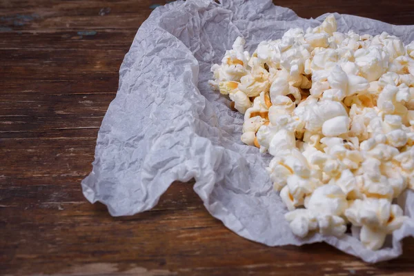 Hromada Hotového Popcornu Bílém Papíře Hnědý Dřevěný Stůl Pozadí — Stock fotografie