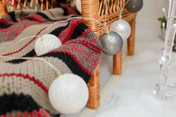 銀と白の電球ウィッカーの家具にニットのスカーフのついた赤ん坊を閉じます クリスマス装飾インテリアの詳細 — ストック写真