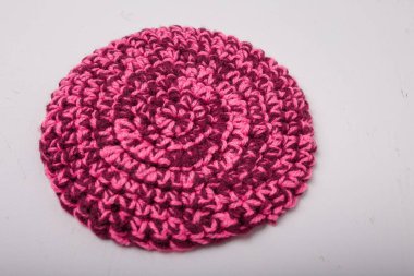 Beyaz arka planda sıcak fincanlar için yuvarlak örülmüş melanj pembe paspas, yakın plan çekim