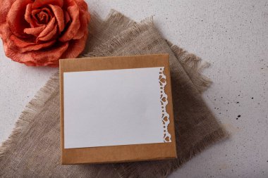 Kahverengi karton hediye kutusu, kumaş gül çiçeği, beyaz arka planda boş kartpostal. Sevgililer günü, doğum günü ya da düğün sürprizi