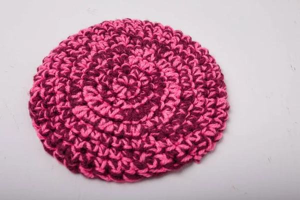 Beyaz arka planda sıcak fincanlar için yuvarlak örülmüş melanj pembe paspas, yakın plan çekim