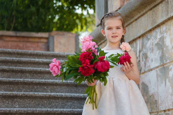 Красивая Маленькая Девочка Белом Платье Стоящая Лестнице Большим Букетом Пионов — стоковое фото