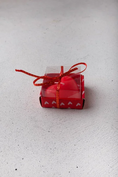 Red heart-shaped candle in box on white background. Small Valentines day present, symbol or souvenir. Copy space