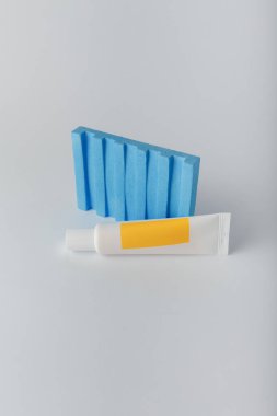 Parlak boş etiketli kozmetik makyaj tüpü. Meyveli krema, böğürtlen, beton dekorlu beyaz üzerine bitkisel vitamin özü. Uzayı kopyala, dikey