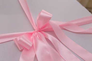 Yumuşak pembe kurdeleli beyaz hediye kutusu, yakın çekim. Düğün, doğum günü, sevgililer günü hediyesi, anne, kadınlar günü hediyesi.