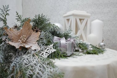 Güzel Noel süslemeleri, köknar dallarında beyaz takılar, fener ve beyaz masada mumlar. Kış tatili, yeni yılın büyüsü