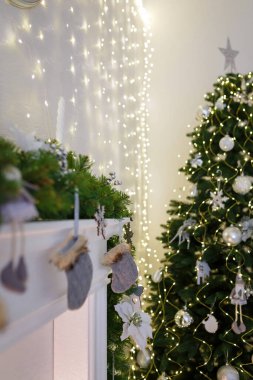 Şöminede asılı gri Noel çorabı, arka planda güzel süslenmiş köknar ağacı, dikey çekim