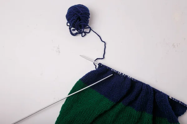 针织服装 制作过程中的饰品 针织针头 白色背景的纱线 带蓝色 绿色的布 — 图库照片