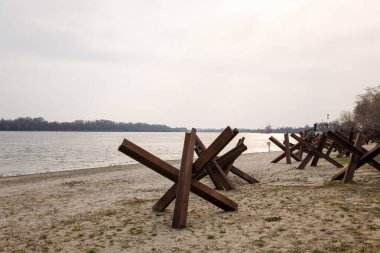 Nehir kıyısında askeri tanksavar kirpileri. Metalik barikat ya da savunma için engel. Ukrayna 2022 'de savaş. Rus saldırganlığı