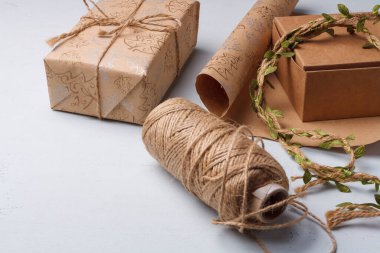 Çevre dostu Noel hediyeleri paketleniyor. Doğal Yeni Yıl dekorasyonları hakkında farkındalık. Kağıt rulo, ip makarası beyaz masada.