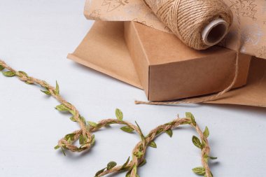 Doğal toprak renkli kağıt ve Noel hediyeleri için çevre dostu dekoratif unsurlar, beyaz masada jüt halat makarası.