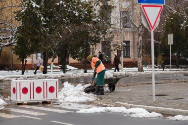İzmail, Ukrayna. Şubat 2022. Temizlikçi ya da temizlikçi, sokakları kardan gösteriş ve el arabasıyla temizliyor. Kışın karlar kalkar.