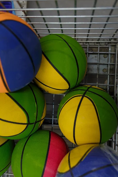 Several bright basketball balls in shopping trolley, colorful sports equipment in supermaket or sports store. Top view