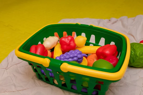 Basket of plastic vegetables toys on carpet in child room. Educational toys, early development, preschool activity.