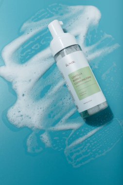 İzmail, Ukrayna. Mart 2022. IUNIK Centella baloncuk temizleyici köpük şişesi mavi arka planda. Kore yüz bakımı kozmetik dokusu
