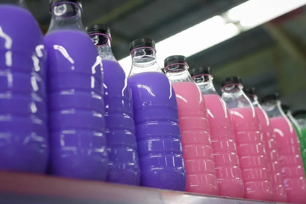 Colorful purple and pink detergents bottles on supermarket shelf. Housekeeping cleaning equipment, containers with no brand, mock up
