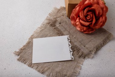 Kahverengi karton hediye kutusu, kumaş gül çiçeği, beyaz arka planda boş kartpostal. Sevgililer günü, doğum günü ya da düğün sürprizi
