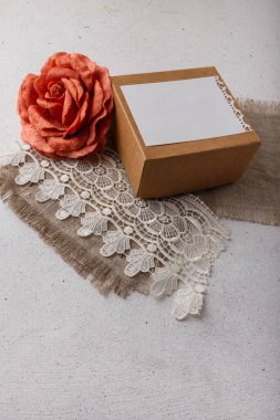 Brown paper present box, fabric rose flower, blank postcard, sackcloth and lace on white background. Valentines day, birthday, wedding