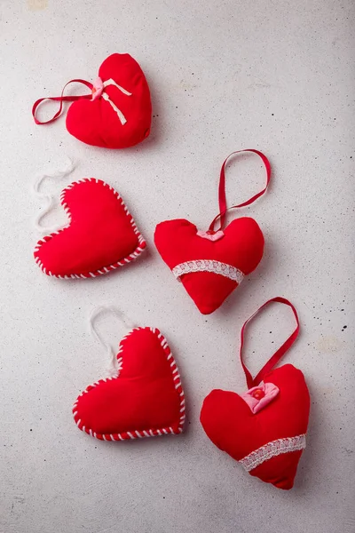 Red fabric sewn hearts soft toys on white background. Valentines day small souvenirs, Christmas tree toys with lace, buttons