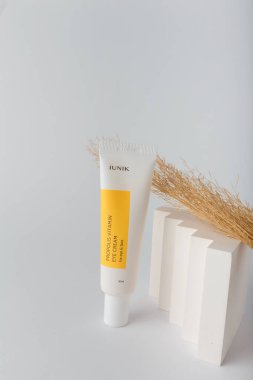 İzmail, Ukrayna. Mart 2022. IUNIK Propolis göz ve yüz için vitamin kremi. Beyaz arka planda sazlıklar ile kozmetik tüpü