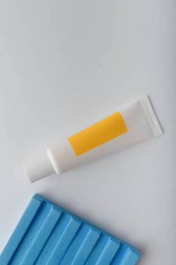 Parlak boş etiketli kozmetik makyaj tüpü. Meyveli krema, böğürtlen, beton dekorlu beyaz üzerine bitkisel vitamin özü. Uzayı kopyala, dikey