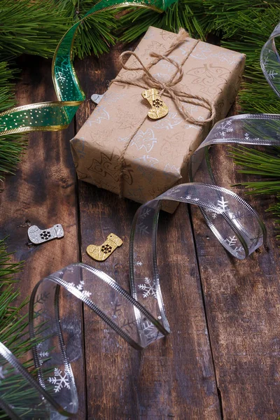 メリークリスマス ハッピーニューイヤープレゼントボックスクラフト紙に包まれ 松の枝 暗い木製の背景に銀リボンテープ — ストック写真