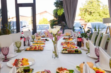 İzmail, Ukrayna. Ekim 2021. Aperatifli şölen masası. Salatalar, peynir ve et tabakları. Restorandaki misafirler için boş bardaklar, tabaklar, sandalyeler.