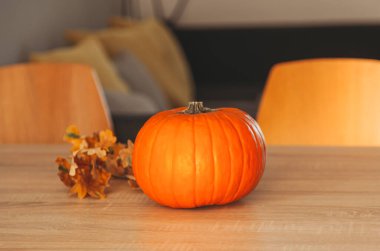 Odadaki masada portakal kabağı ve sonbahar yaprakları. Merhaba sonbahar, rahat ve yavaş yaşam. Mutlu Şükran Günleri.