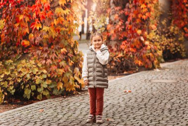 Güzel küçük kız sonbahar parkında dinleniyor.