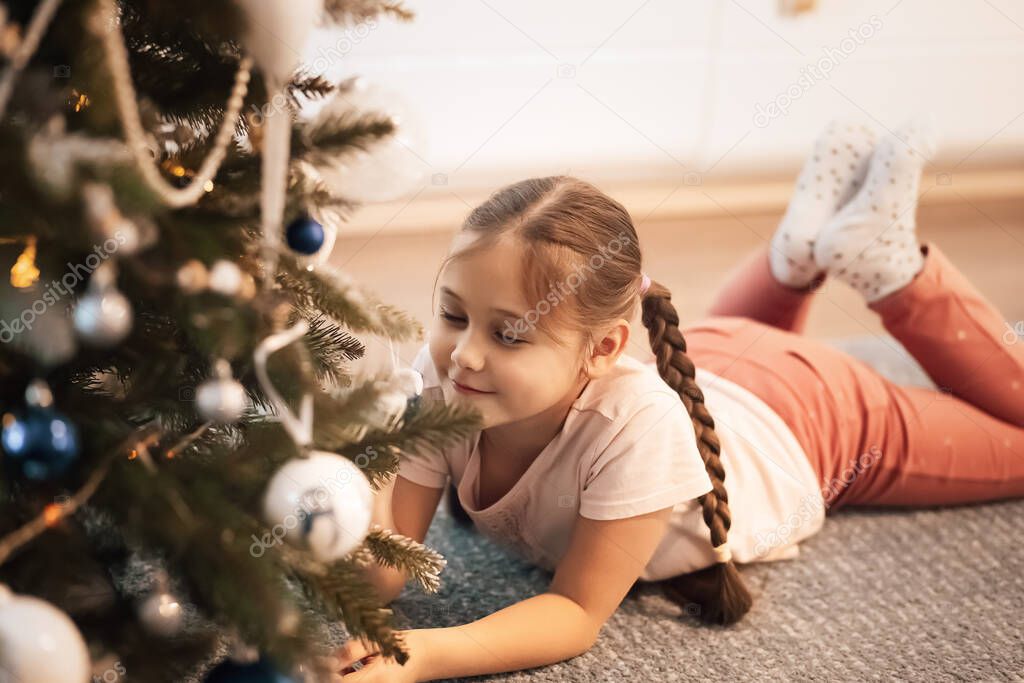 Pretty girl  lying and smiling near christmas tree. Christmas concept.