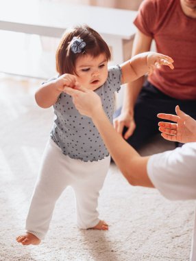Sevimli küçük bir kızın portresi evde annesinin elini tutarak yürümeyi öğreniyor, küçük çocuk ilk adımlarını destekle, çocuk bakımıyla, yetiştirme konseptiyle atıyor.